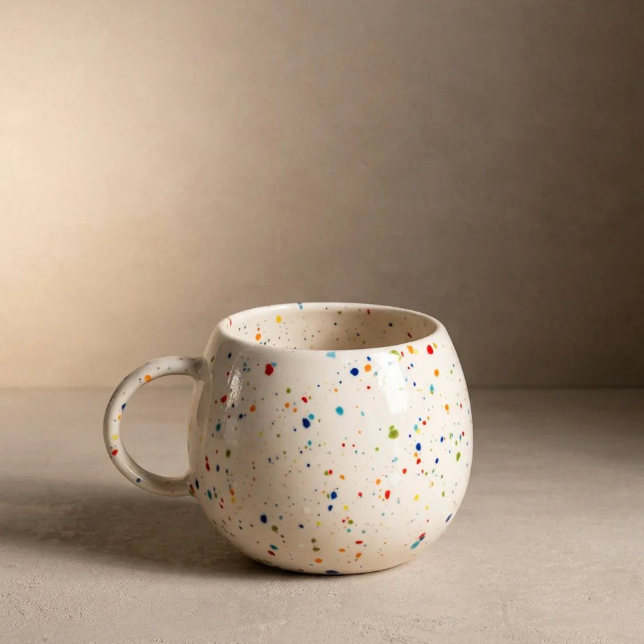Speckled ceramic mug on a beige surface with a neutral background