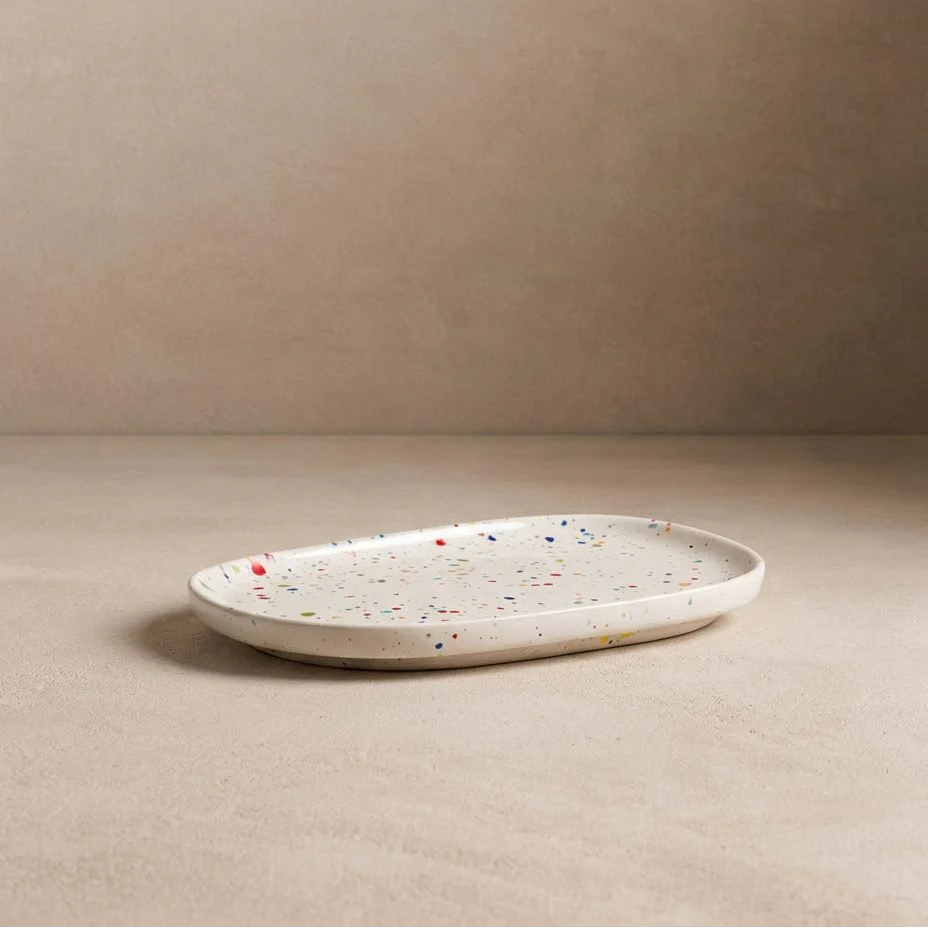 White ceramic plate with speckled pattern on a beige surface and background