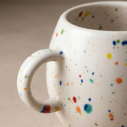White mug with colorful speckles on a beige background