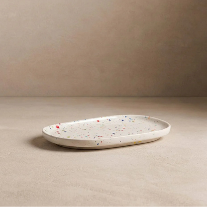 White ceramic plate with speckled pattern on a beige surface and background